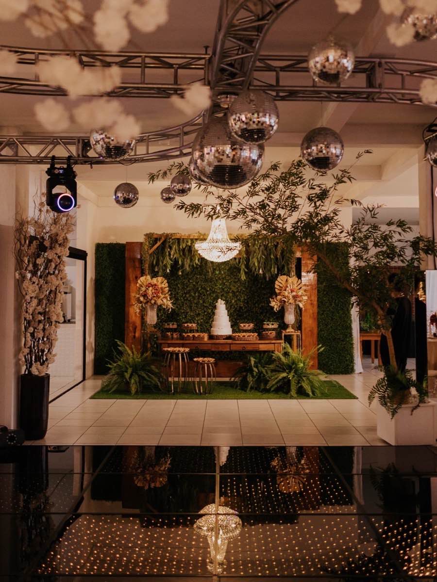 Salão com pista de dança espelhada, globos espelhados e mesas decoradas ao redor